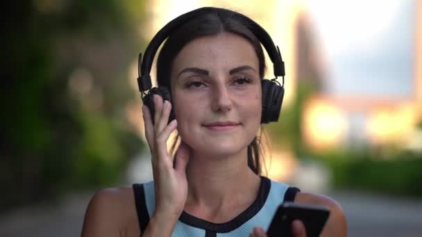Kız koyar kulaklıktan içerir ve telefonda müzik dinler ve dans. yakın çekim. 4k — Stok video