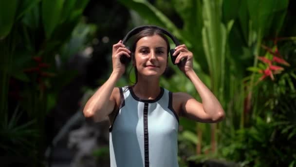 Chica se pone los auriculares incluye y escucha música en el teléfono y bailando. Primer plano. 4k — Vídeo de stock