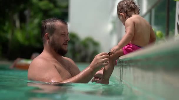 A cute little baby and his father are playing in the pool. — Stock Video