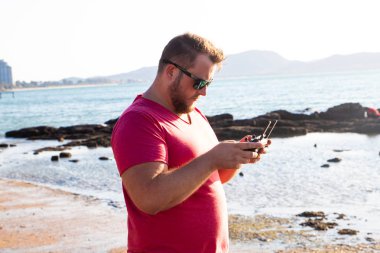 Bir adam bir dron günbatımında denetler.