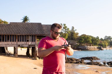 Bir adam bir dron günbatımında denetler.