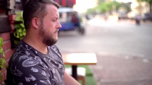 Hombre barbudo hablando por teléfono y charlando en un café en la calle. 4k . — Vídeos de Stock