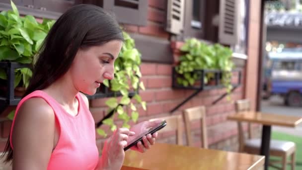 Mulher a falar ao telefone, envia mensagens num café na rua. 4k — Vídeo de Stock