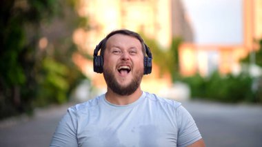 Sakallı komik adam giysilerini üzerinde koyar, müzik döner, enerjik müzik, dans etmek dinliyor. Yakın çekim