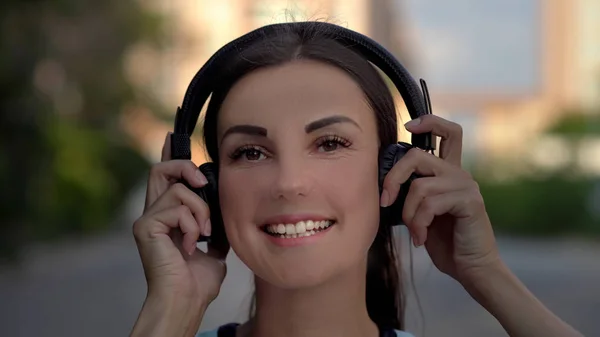 O tânără frumoasă care folosește telefonul inteligent, tastează mesaje, ascultă muzică, bea cafea în timp ce se plimbă pe strada urbană. Close up — Fotografie, imagine de stoc