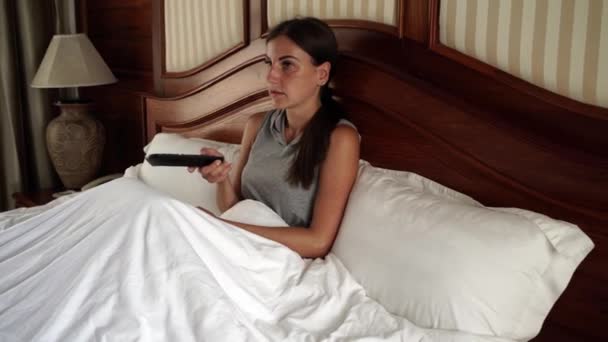 Γυναίκα ξαπλωμένη στο κρεβάτι βλέποντας τηλεόραση. 4k. — Αρχείο Βίντεο