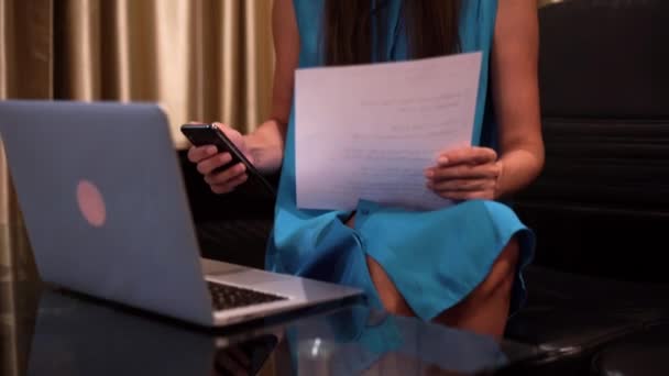 一位年轻女子正在一张装有文件的黑色桌子上拿着笔记本电脑工作。4k. — 图库视频影像
