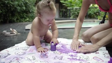 Çocuk annesiyle parmak boyaları bahçedeki havuzun boyar. Çocuk geliştirme kavramı. 4k.