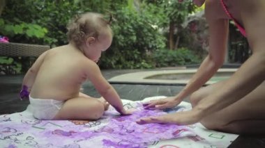 Çocuk annesiyle parmak boyaları bahçedeki havuzun boyar. Çocuk geliştirme kavramı. 4k.