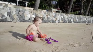 Kız sahilde kum bir yıl oynar. Konsept: çocuk, çocukluk, yaz, özgürlük, çocuk, bebek. 4k.