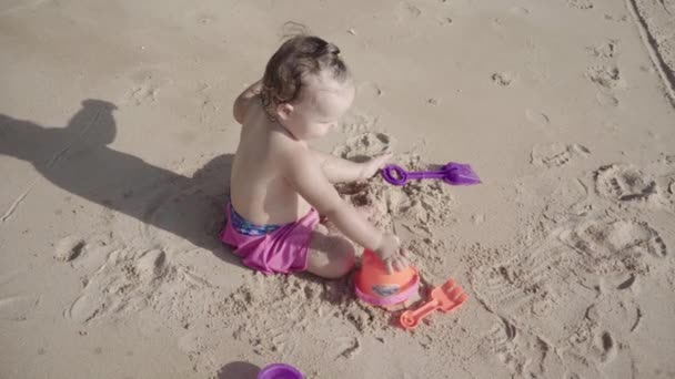 Kız sahilde kum bir yıl oynar. Konsept: çocuk, çocukluk, yaz, özgürlük, çocuk, bebek. 4k. — Stok video