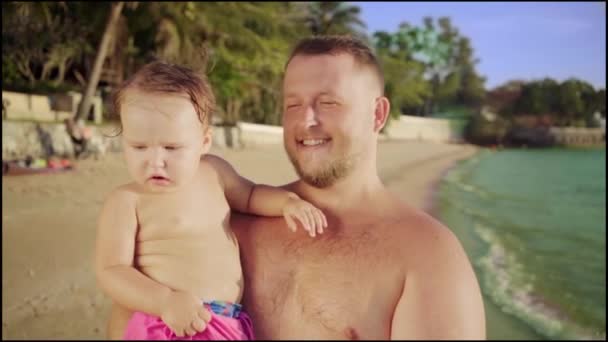 Šťastný otec nese v náručí roztomilé dítě na krásné pláži v Thajsko, Pattaya. 4k. — Stock video