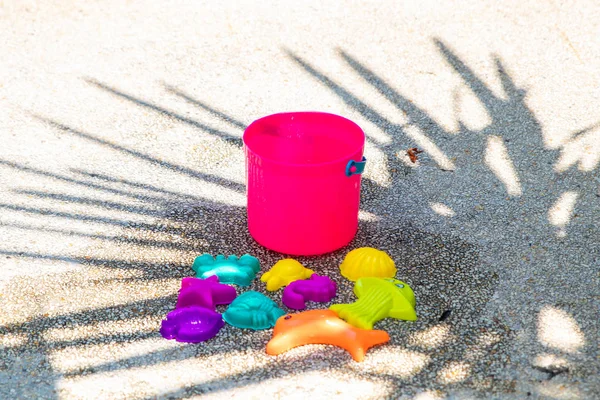 childrens beach bright pink toys on a sandy concrete background.