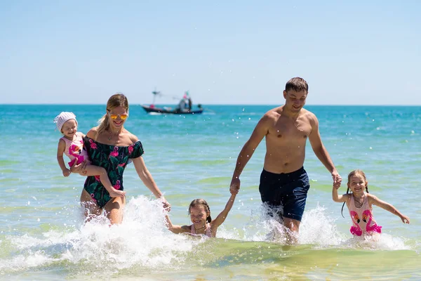 Gruppo di bambini felici che giocano e schizzano sulla spiaggia del mare. I bambini si divertono all'aperto. Vacanza estiva e concetto di stile di vita sano . — Foto Stock