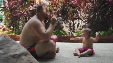 Baba ve kız havuz tarafından bahçede sabun kabarcıklar üfleme, yavaş hareket