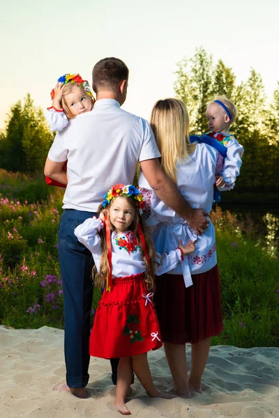 Grande família nos trajes étnicos ucranianos sentar-se no prado, o conceito de uma grande família. vista para trás — Fotografia de Stock