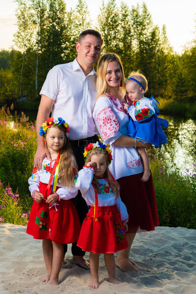 large family in ethnic Ukrainian costumes sit on the meadow, the concept of a large family.
