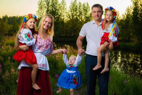 large family in ethnic Ukrainian costumes sit on the meadow, the concept of a large family.