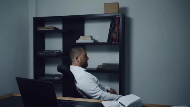Бородатый бизнесмен крутится в офисном кресле на работе, мужчина скучает и мечтает, замедленная съемка — стоковое видео