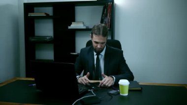 dizüstü bilgisayarın arkasındaki ofiste oturan işadamı vurguladı, erkek işçi telefon ve alır kızgın, yavaş hareket görünüyor.