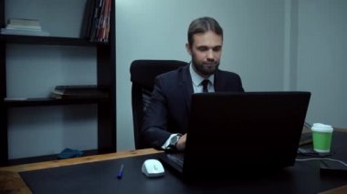Sakallı işadamı, dizüstü bilgisayar ofiste erkek işçi düşünüyor ve sürpriz, ağır çekim oturan.