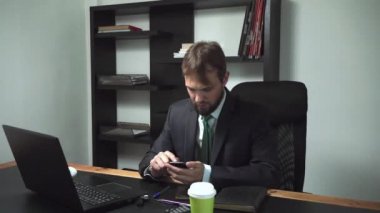 dizüstü bilgisayarın arkasındaki ofiste oturan işadamı vurguladı, erkek işçi telefon ve alır kızgın, yavaş hareket görünüyor.