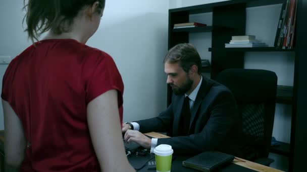 Homem de negócios barbudo sentado no escritório no laptop, menina de vermelho está tentando seduzir o chefe, câmera lenta . — Vídeo de Stock