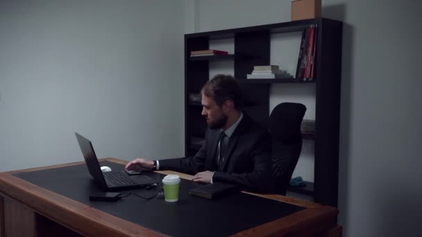 Homem de negócios barbudo sentado no escritório, trabalhador masculino assistindo filmes no telefone no trabalho, câmera lenta . — Vídeo de Stock