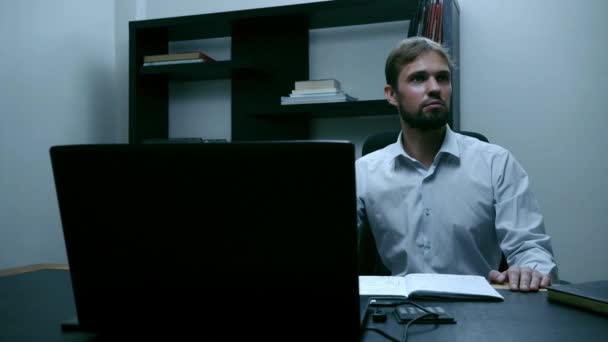 Bearded businessman sitting in the office at the laptop, male worker thinks and surprised, slow motion. — Stock Video