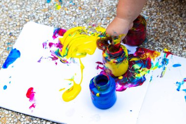 Çocuk el parmak boya - mavi, kırmızı ve sarı beyaz bir kağıt üzerine çizer. Anaokulu veya serbest zaman evde yaratıcı çocuk gelişimi