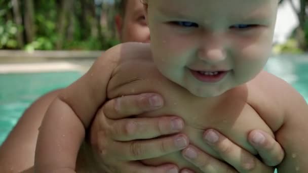 Schattige kleine jongen en zijn vader hebben een les zwemmen in het zwembad. Closeup portret van een meisje — Stockvideo