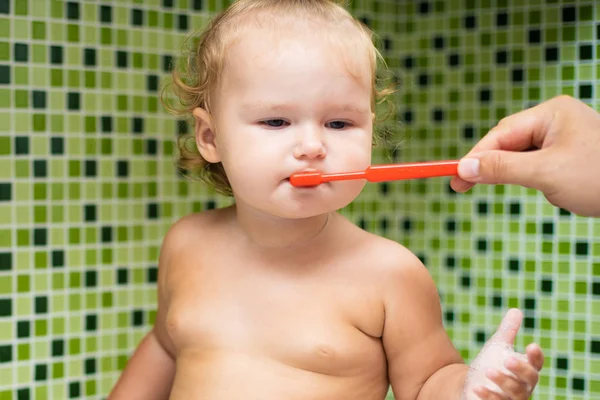 Söta barn girl borsta hennes tänder i badrummet. Söt baby sitter i diskhon. Pappa hjälper till att borsta barnets tänder — Stockfoto