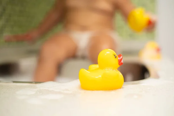Κίτρινο πάπια, στο φόντο ένα παιδί στο νεροχύτη είναι εκτός εστίασης — Φωτογραφία Αρχείου