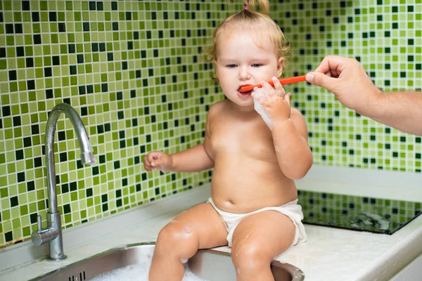 可爱的幼儿女孩刷牙在浴室。可爱的婴儿坐在水槽里。爸爸帮孩子刷牙 — 图库照片
