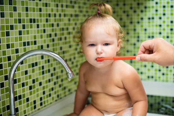 Χαριτωμένο μικρό παιδί κορίτσι βουρτσίζετε τα δόντια της στο μπάνιο. Χαριτωμένο μωρό κάθεται στο νεροχύτη. Ο μπαμπάς σας βοηθά να βουρτσίζετε τα δόντια του παιδιού — Φωτογραφία Αρχείου