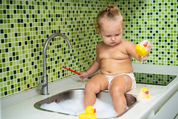 Linda niña cepillándose los dientes en el baño. Lindo bebé sentado en el fregadero . — Foto de Stock