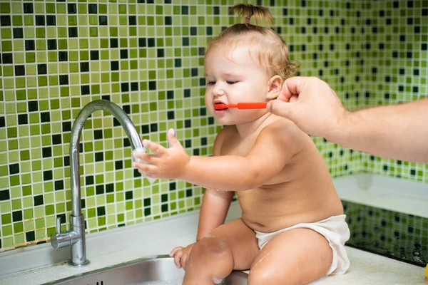 Dziewczyna słodkie małe dziecko szczotkowanie zębów w łazience. Słodkie dziecko siedzi w zlewie. Tata pomaga szczotkować zęby dziecka — Zdjęcie stockowe