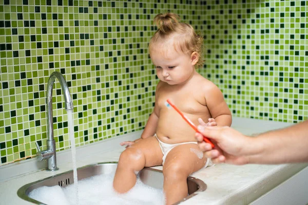 Dziewczyna słodkie małe dziecko szczotkowanie zębów w łazience. Słodkie dziecko siedzi w zlewie. Tata pomaga szczotkować zęby dziecka — Zdjęcie stockowe