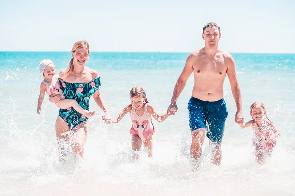 Gruppo di bambini felici che giocano e schizzano sulla spiaggia del mare. I bambini si divertono all'aperto. Vacanza estiva e concetto di stile di vita sano . — Foto Stock