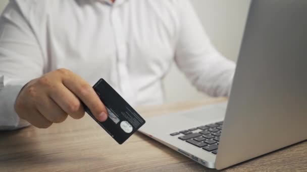 Διαδικτυακή ιδέα για ψώνια. άνθρωπος χέρια που κατέχουν πιστωτική κάρτα και τη χρήση φορητού υπολογιστή. αρσενικό χέρι χτυπά την κάρτα στο τραπέζι — Αρχείο Βίντεο
