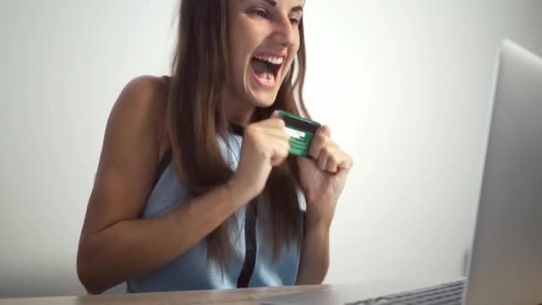 Shopping concetto online. Donna in possesso di una carta di credito e utilizzando il computer portatile. femmina gioisce della carta di credito — Video Stock