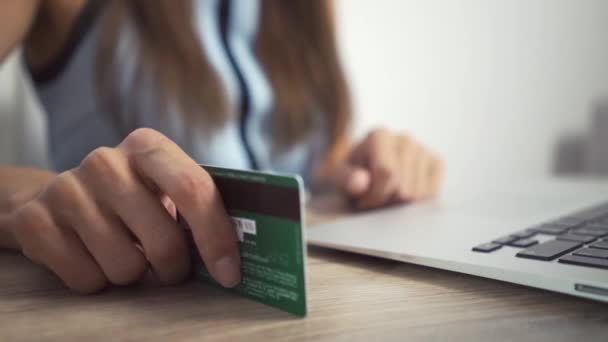 网上购物理念。妇女手拿着信用卡，使用笔记本电脑。女性手敲桌子上的卡 — 图库视频影像