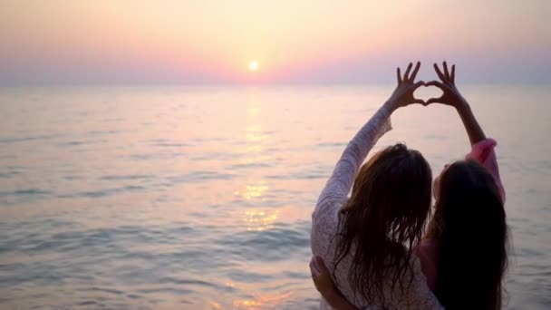 Mujer feliz pareja lesbiana descansando en la hermosa playa tropical. El concepto de LGBT. lesbianas mostrar el corazón al atardecer — Vídeos de Stock