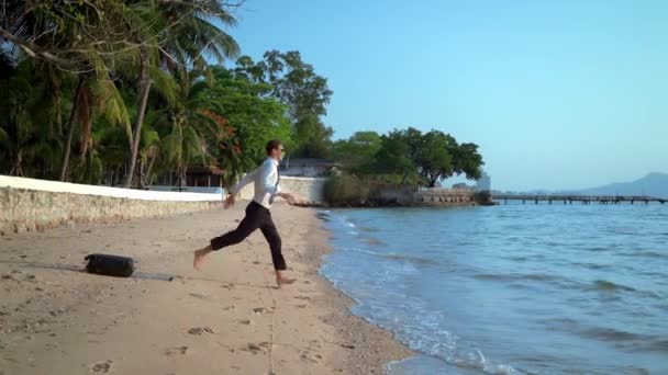 Homem de negócios feliz em um terno e óculos escuros está salpicando no mar em resorts de luxo. conceito de férias bem esperadas, freelancer . — Vídeo de Stock