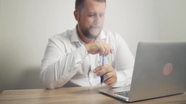 Bebaarde man in een wit overhemd roken van een e-sigaret op een witte achtergrond. Hij is betrokken bij vaping. Slow motion. — Stockvideo
