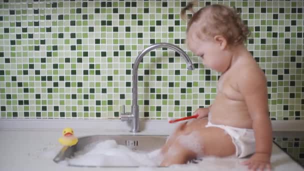 Nettes Kleinkind-Mädchen beim Zähneputzen im Badezimmer. Niedliches Baby sitzt im Waschbecken. — Stockvideo