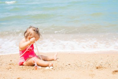 beyaz boncuklu mayo giyen kız şaşırır, sevinir, bağırır, ellerini kaldırır. çocuk moda konsepti.