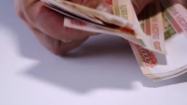 Les mains des hommes comptent l'argent russe, les roubles sur une table blanche .