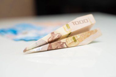 Tay 1000 baht beyaz bir masa üzerinde yatan, bir uçak şeklinde katlanmış