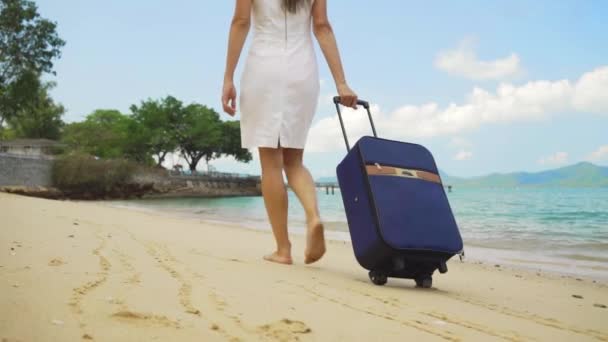 Geschäftsfrau spaziert mit einem Koffer am Ufer eines schönen Meeres entlang. freiberufliches Konzept, langersehntes Freizeitkonzept. — Stockvideo